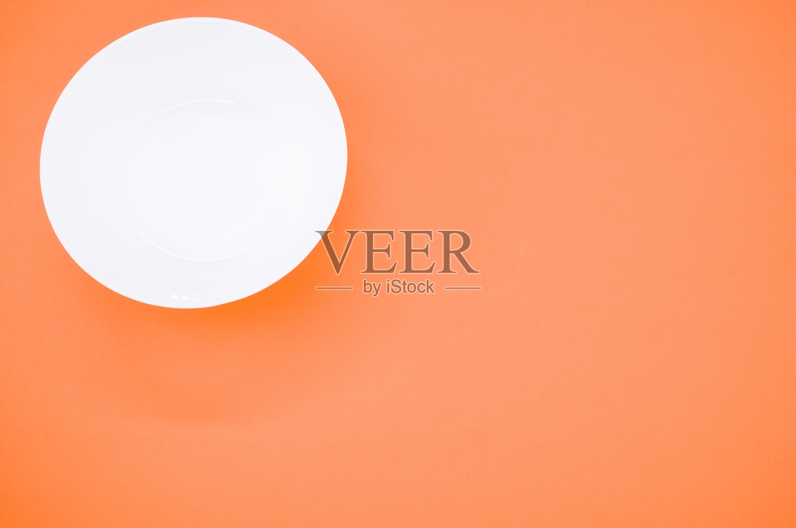 一个空的白色玻璃碗在一个橙色的背景照片摄影图片