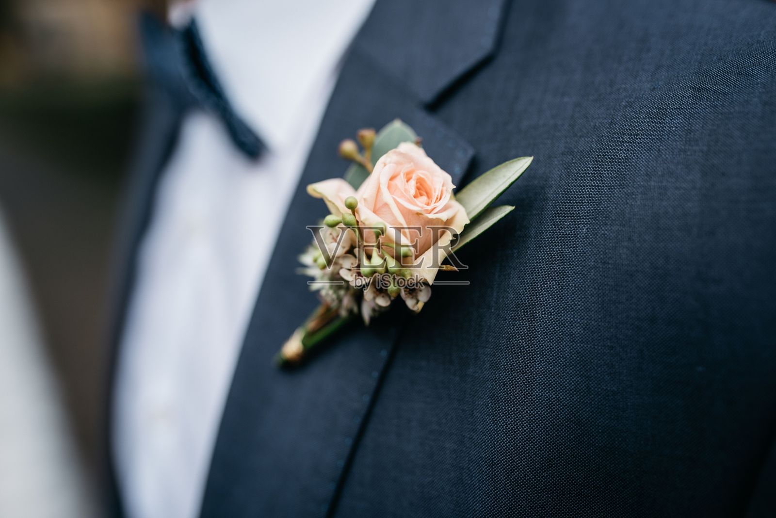 一个男人穿着正装，翻领上有一朵粉红色的花照片摄影图片