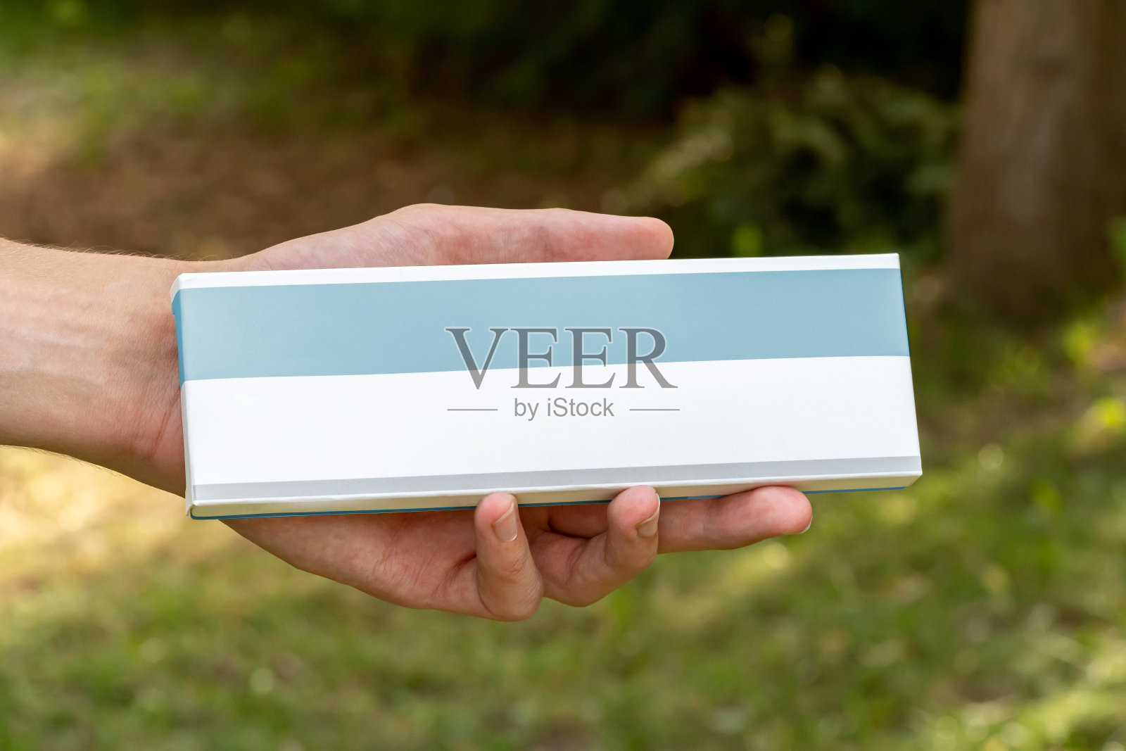 男子手里拿着一个空标签的仿制空白药盒，手里拿着药物包装药丸补充维生素，健康用品盒正面视图，复制太空物体细节特写，一个人照片摄影图片