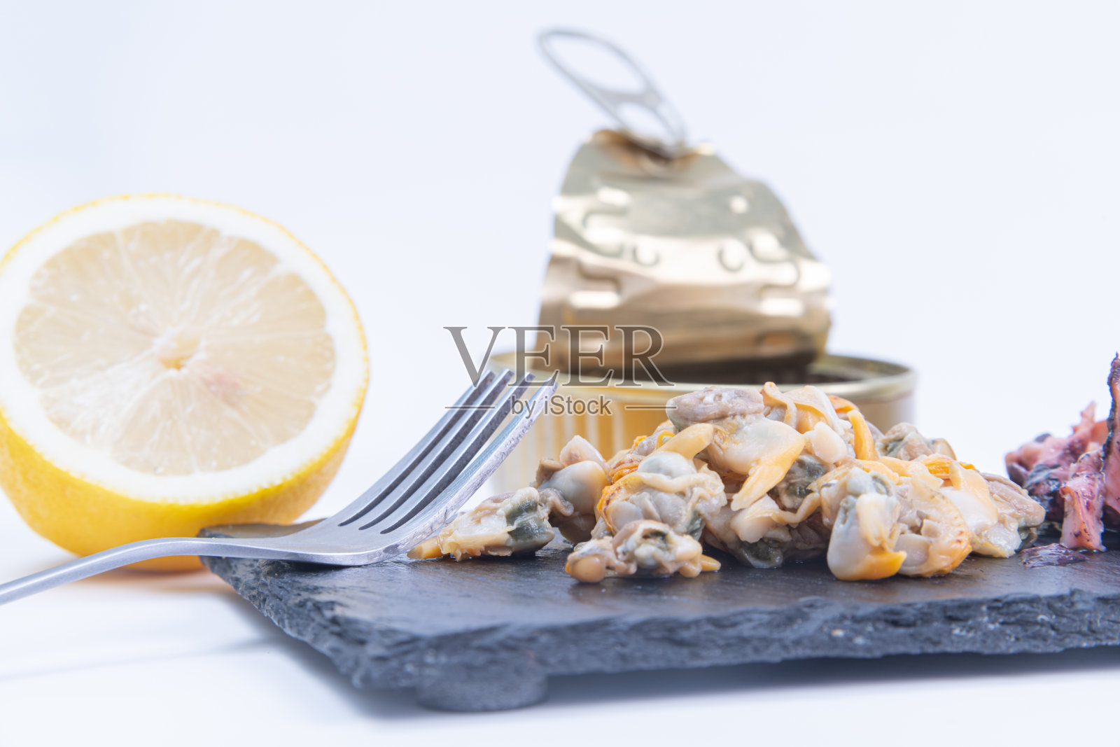 封闭的海鲜罐头和柠檬在一个板上孤立的白色背景照片摄影图片
