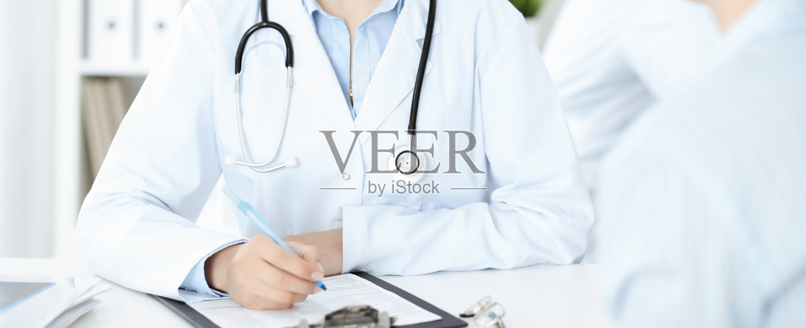 不知名的女医生和病人坐在桌旁。非常好的消息和高水平的医疗服务理念照片摄影图片