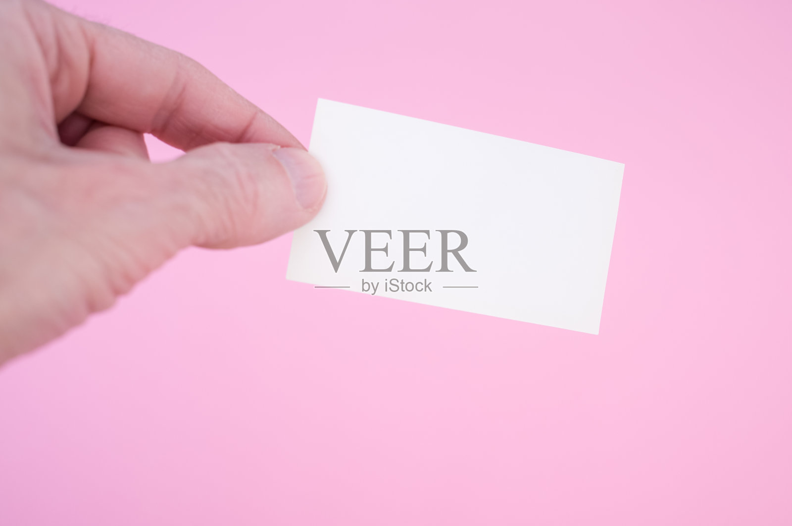 一个人拿着一张空白纸，背景是粉红色的特写镜头照片摄影图片