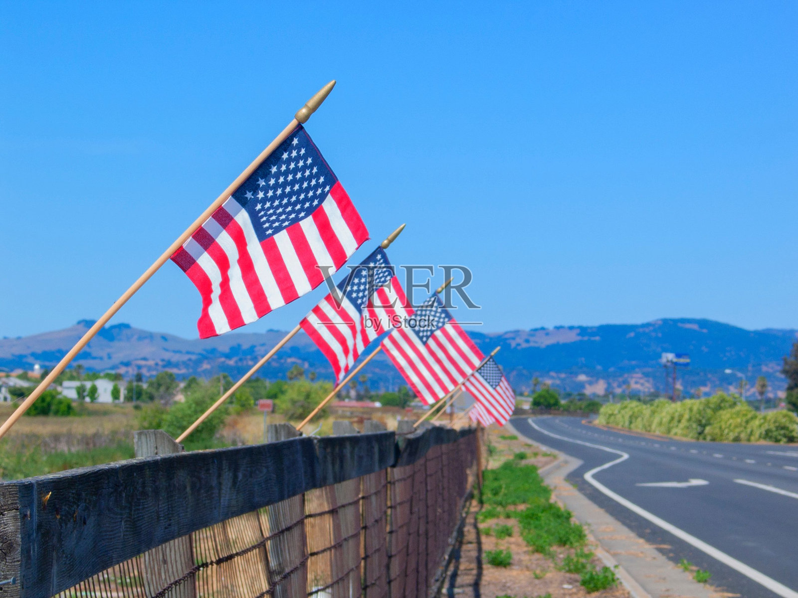 美国国旗在高速公路旁的墙上，背景是山脉照片摄影图片
