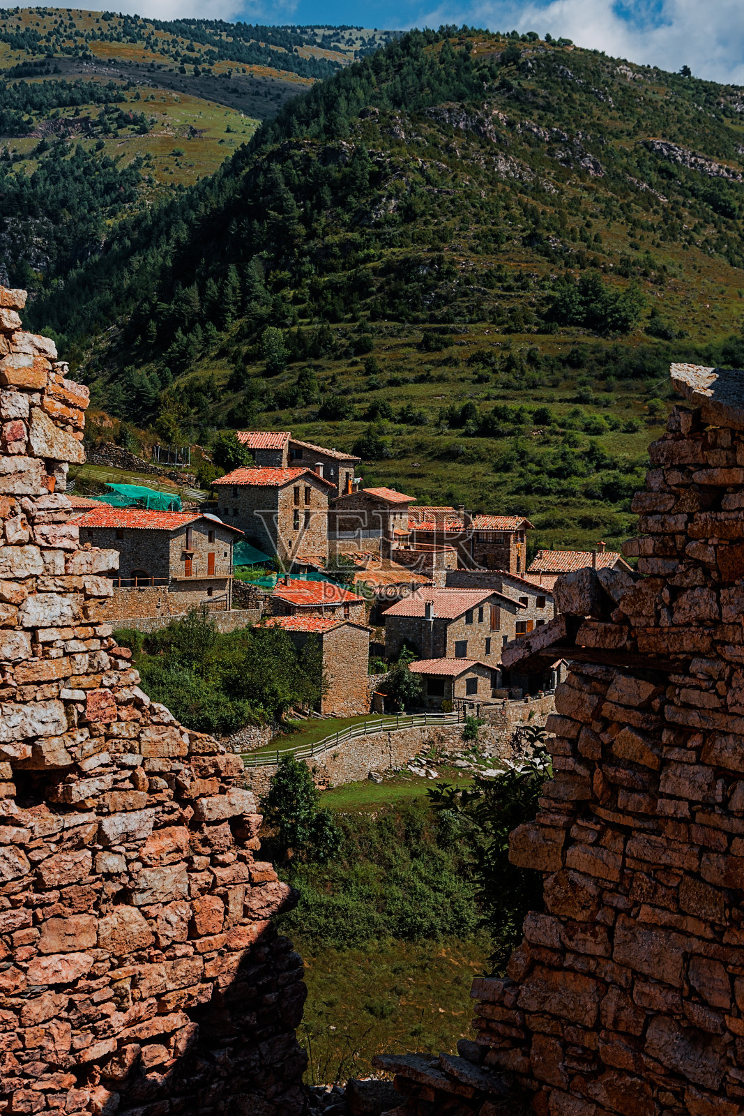 从巨大的墙壁裂缝中捕捉到的建在山坡上的石头房子的垂直镜头照片摄影图片