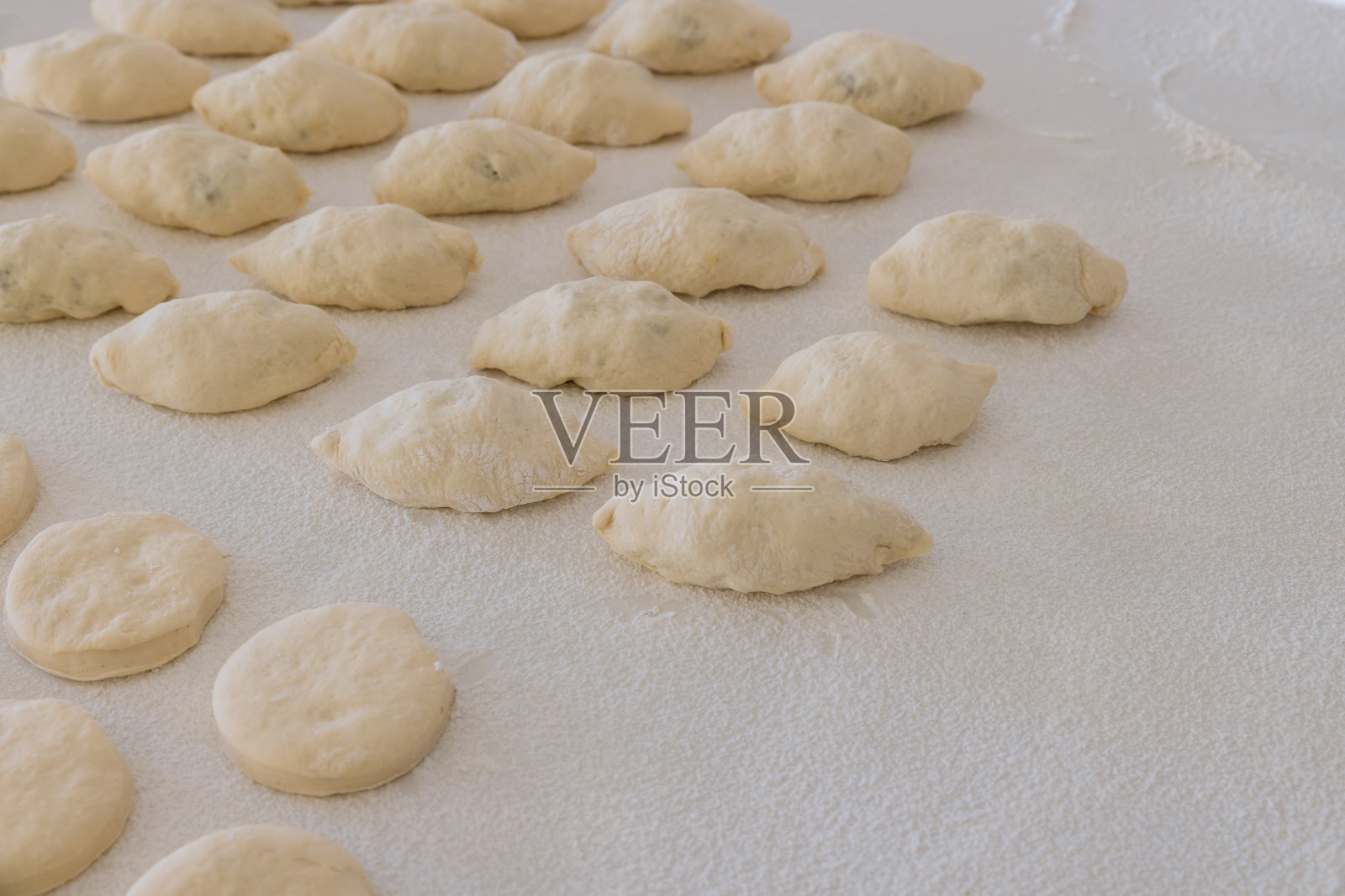 在面团还热的情况下，用白色的工作台面准备酵母面团，用来烤有馅料的面包和甜甜圈照片摄影图片