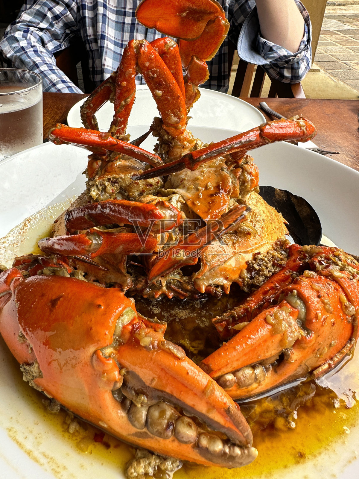 在印度的海鲜美食餐厅，新鲜烤制的整只泥蟹配上大蒜黄油酱和带壳的长柄勺照片摄影图片