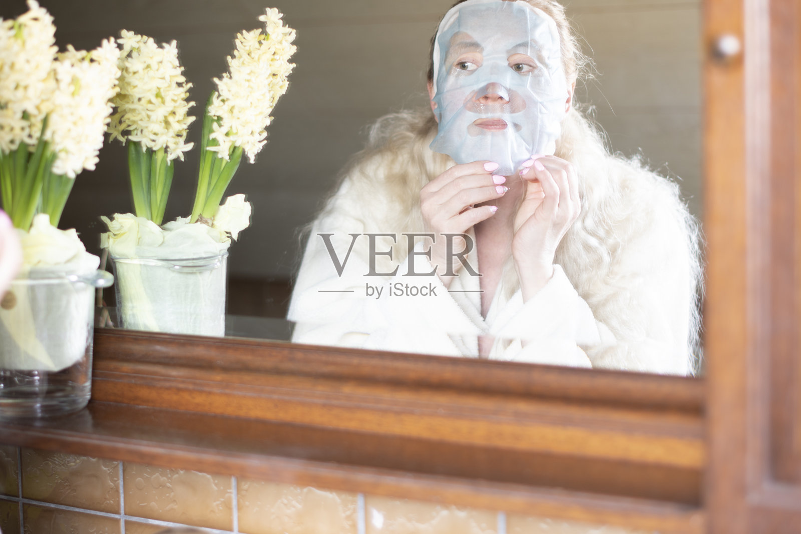 一个中年妇女早上忙着卫生，她做面膜照片摄影图片