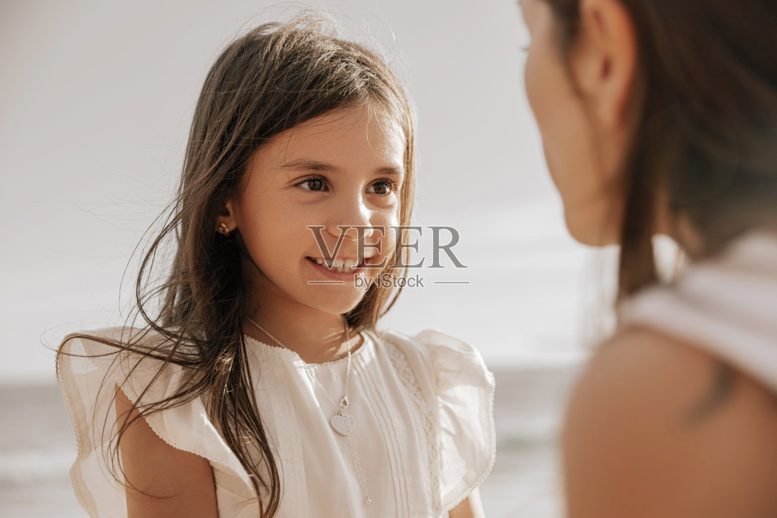 快乐的女儿在海滩上听妈妈说话照片摄影图片