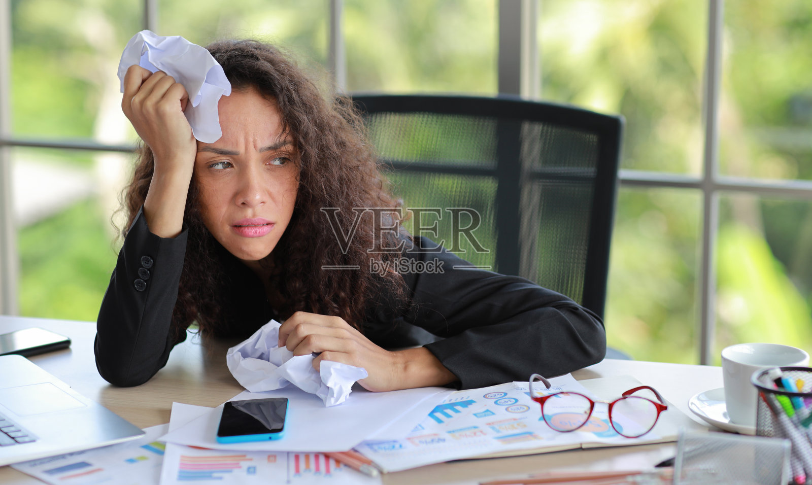 中年成年女商人在听到生意失败或被解雇的坏消息后，在办公室里用揉皱的纸摸着头，在现代办公室里感到沮丧、心烦意乱和绝望。照片摄影图片