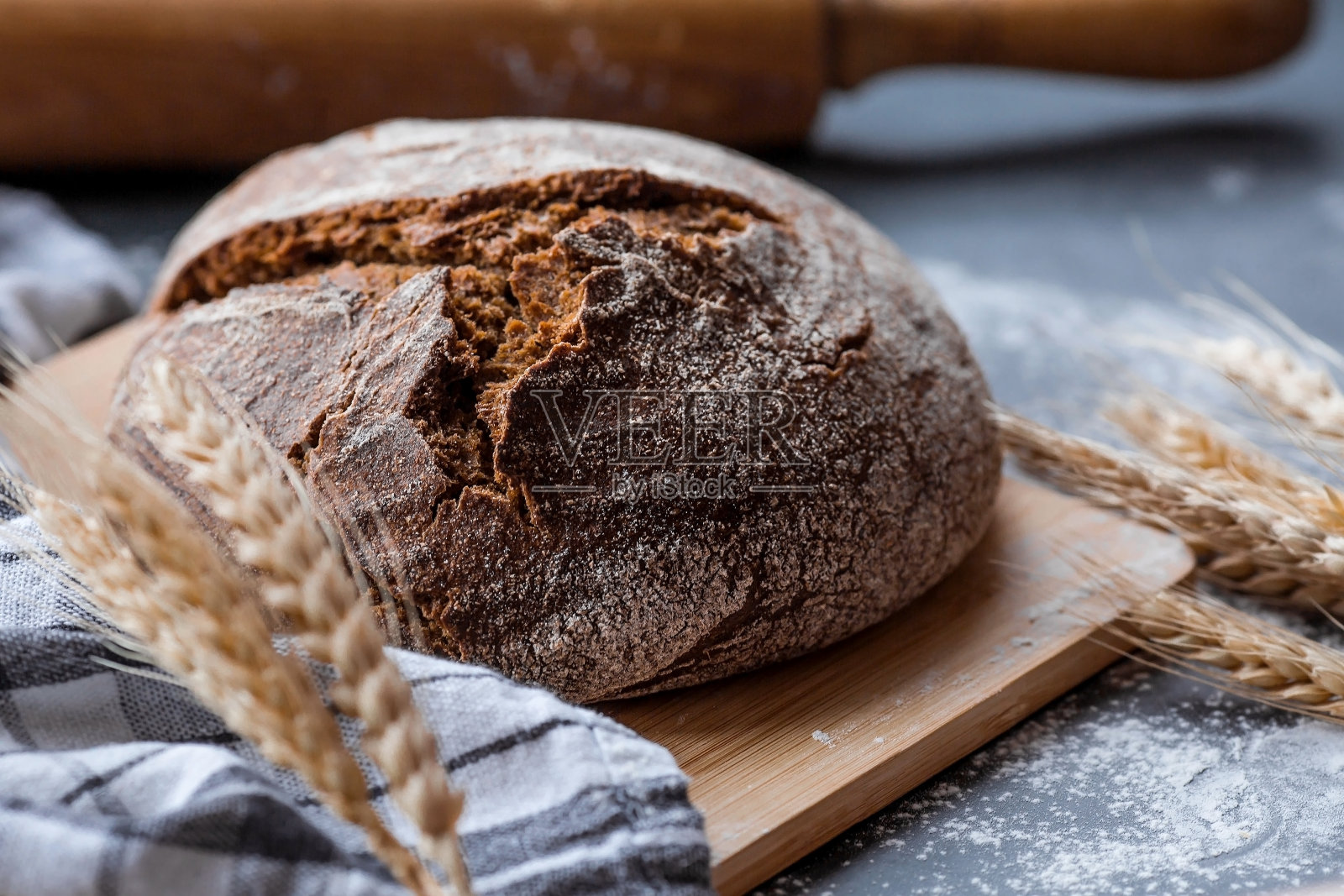 新鲜美味的面包特写。刚烤好的酸面包，金黄色的面包皮放在木板上。面包店里有美味的面包。糖果产品。照片摄影图片