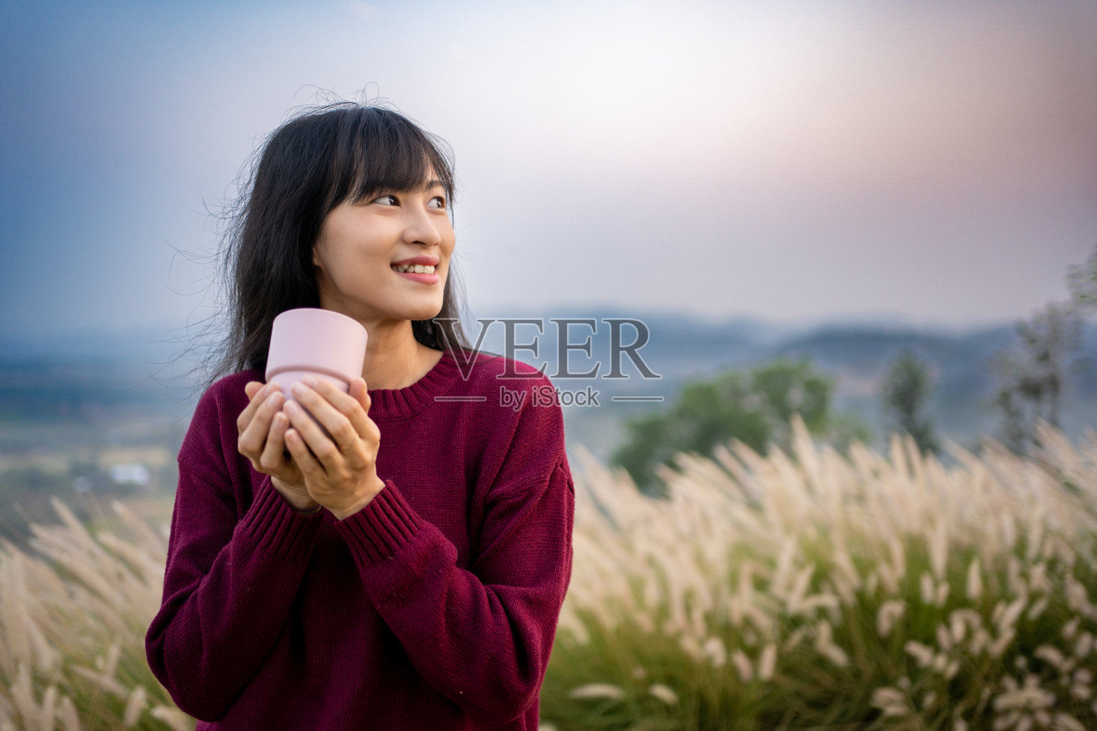 假日期间，亚洲女子在山上喝着热咖啡，享受着风景，具有假日概念。在山上喝咖啡。照片摄影图片