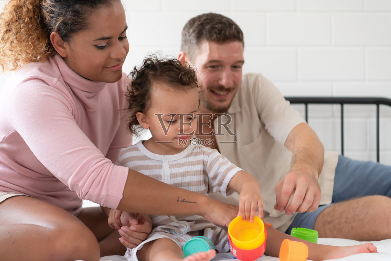 带着小女孩的父母一起在卧室里玩你的新玩具。增强儿童思维能力的玩具。照片摄影图片
