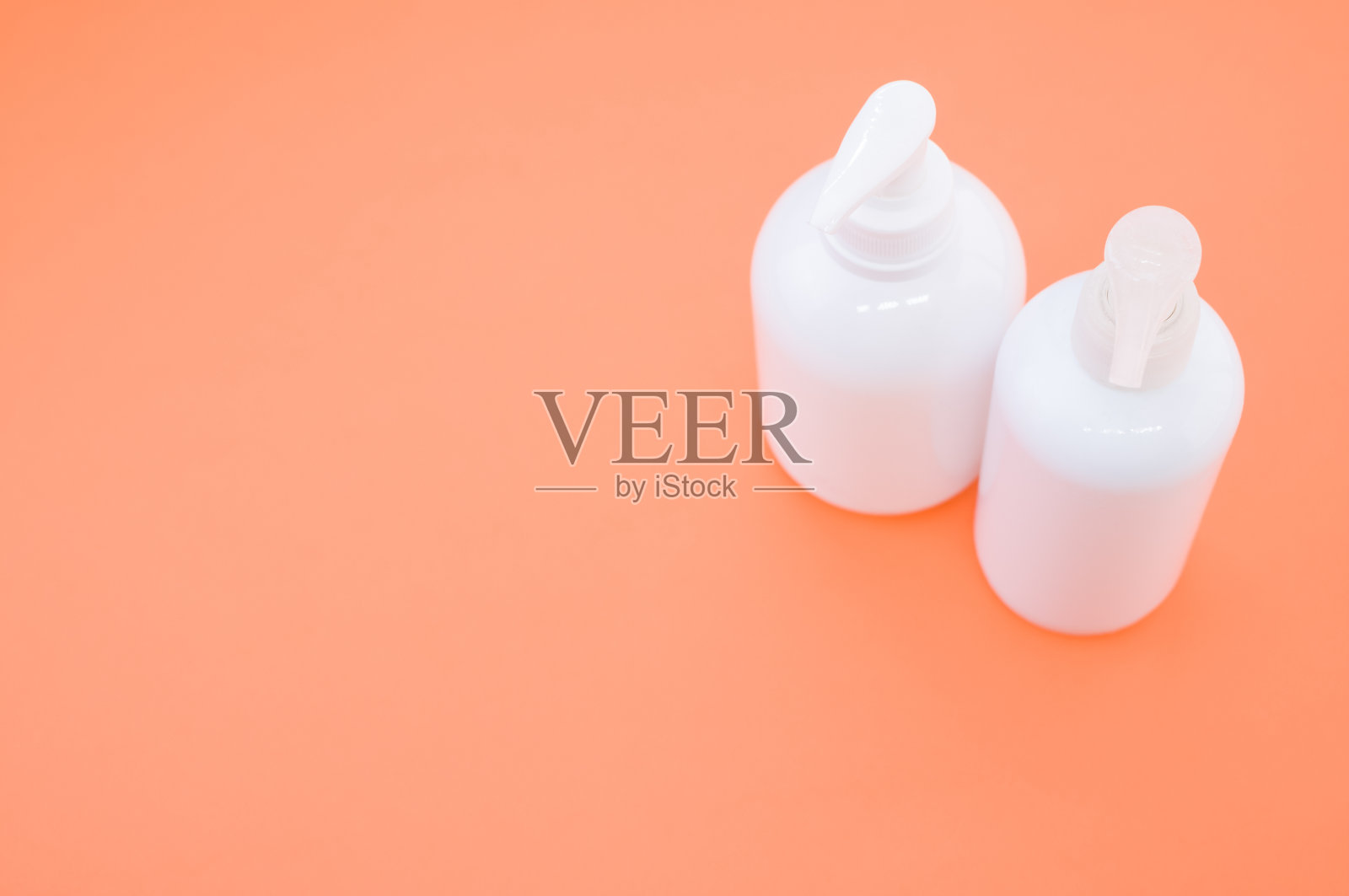 在灯光下，橙色表面上有泵的塑料瓶的高角度拍摄照片摄影图片