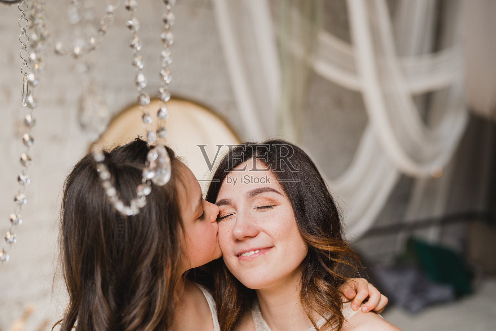 快乐的白人母亲和女儿拥抱，一起在室内玩耍。漂亮的小女孩和漂亮的女人。祝您母亲节快乐。照片摄影图片