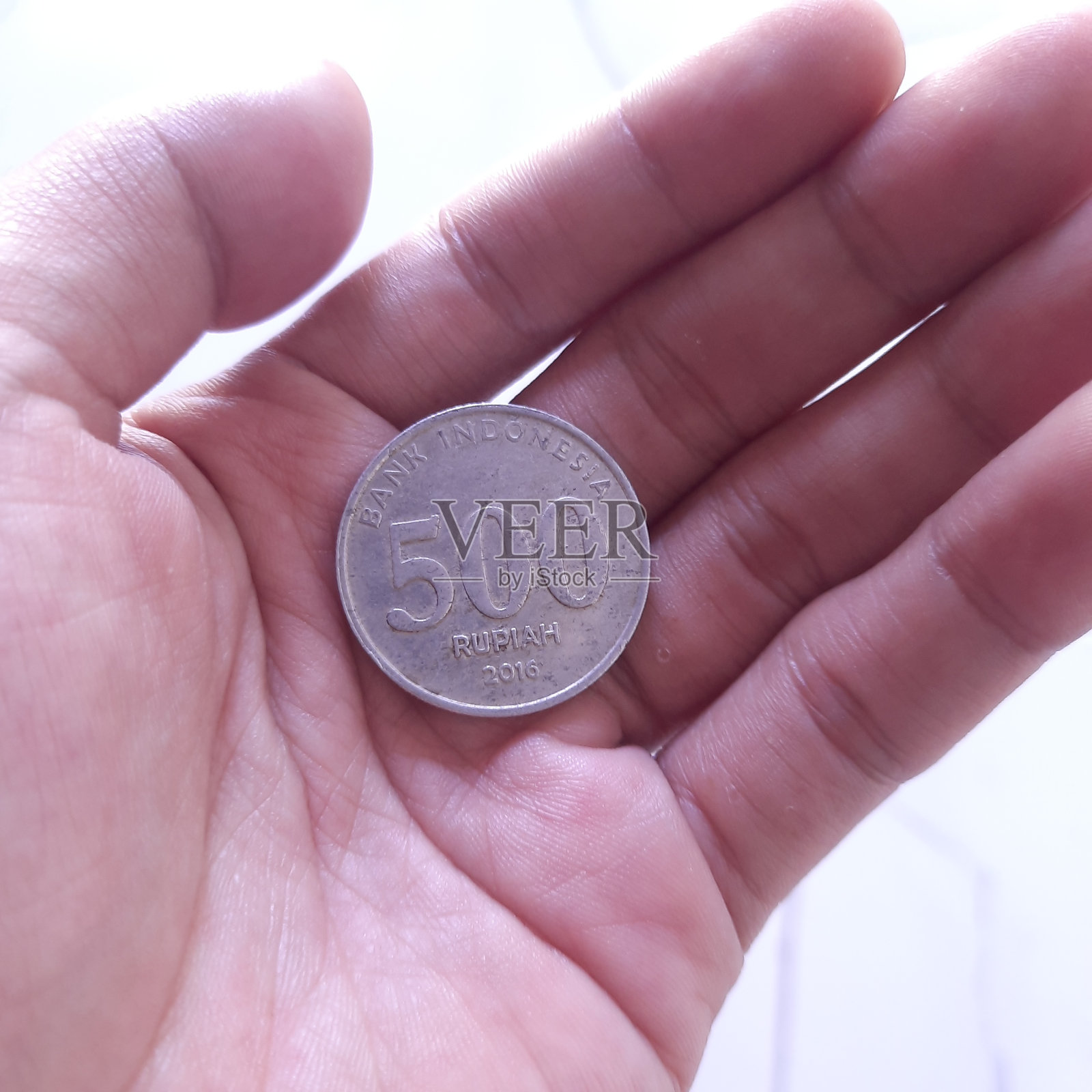 一个人的手拿着2016年发行的价值500卢比的印度尼西亚硬币照片摄影图片