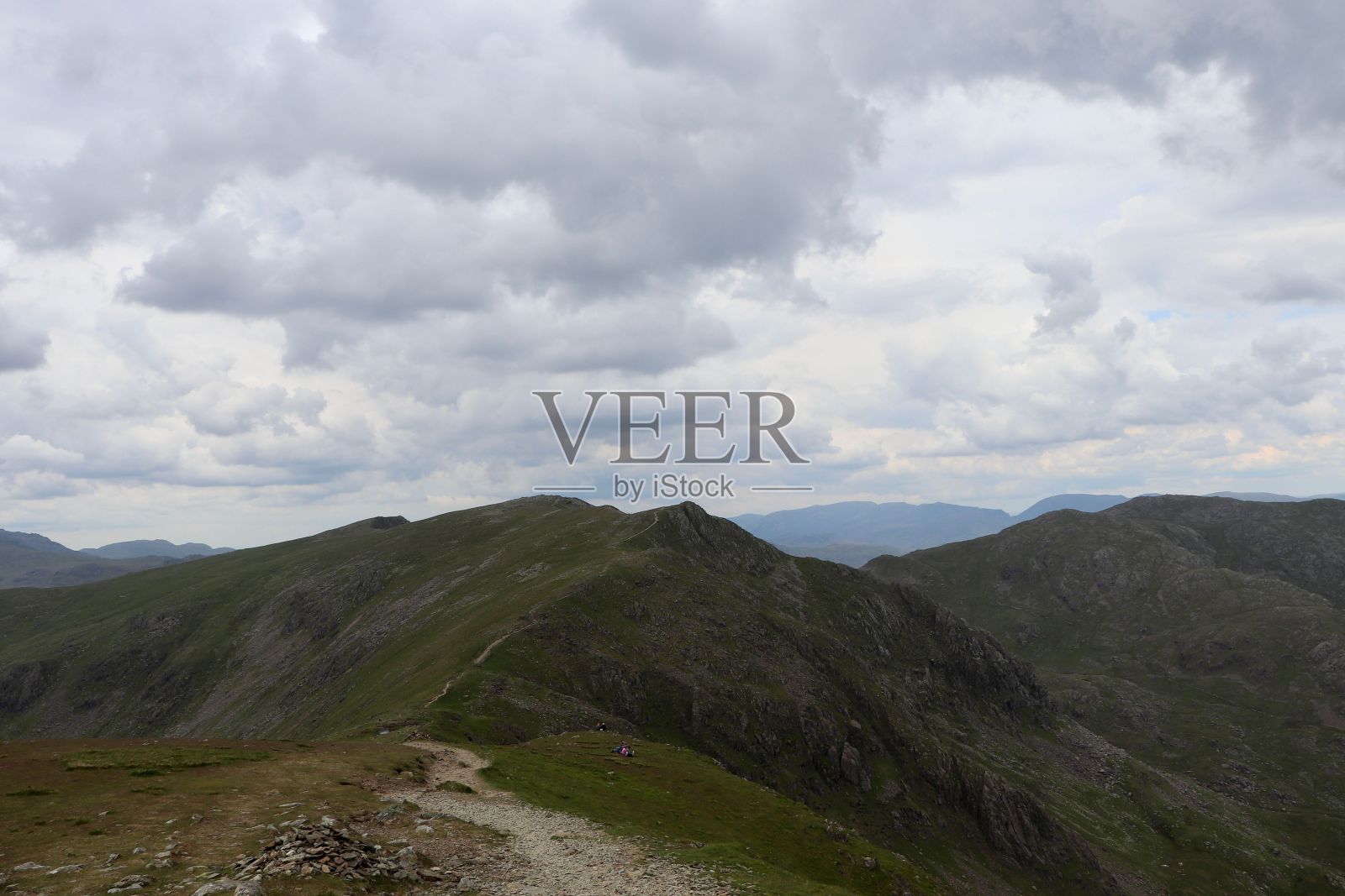 透过多云的大气，可以看到孤立的山峰，远处是山脉照片摄影图片