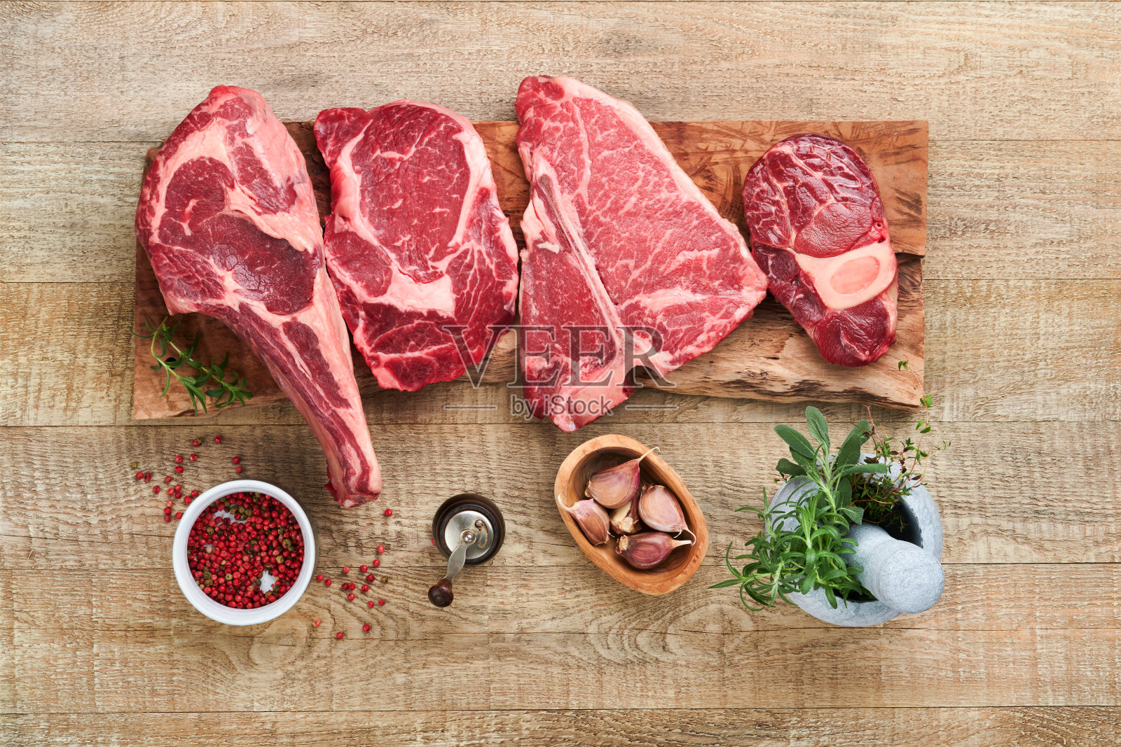 生牛排。各种新鲜的黑安格斯优质肉牛排t骨，纽约，Ribeye, Striploin，战斧砧板上的旧木制背景。各种经典牛排。前视图。照片摄影图片