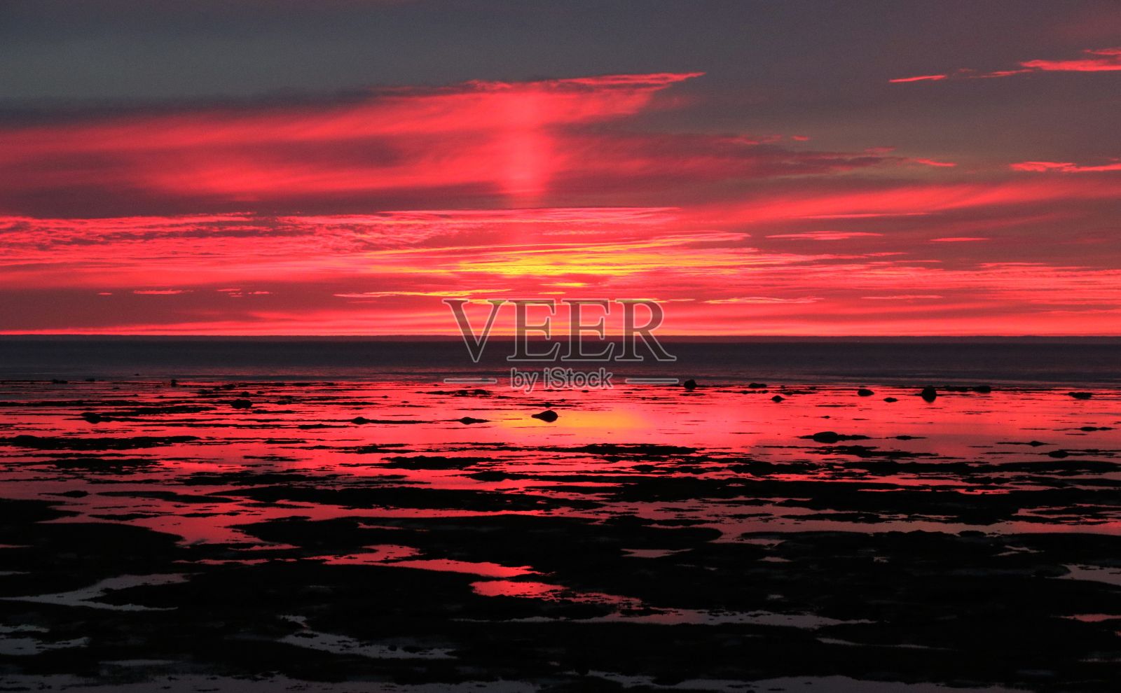 壮观的日落在海面上，充满活力的橙色和粉红色填满了地平线上的天空照片摄影图片