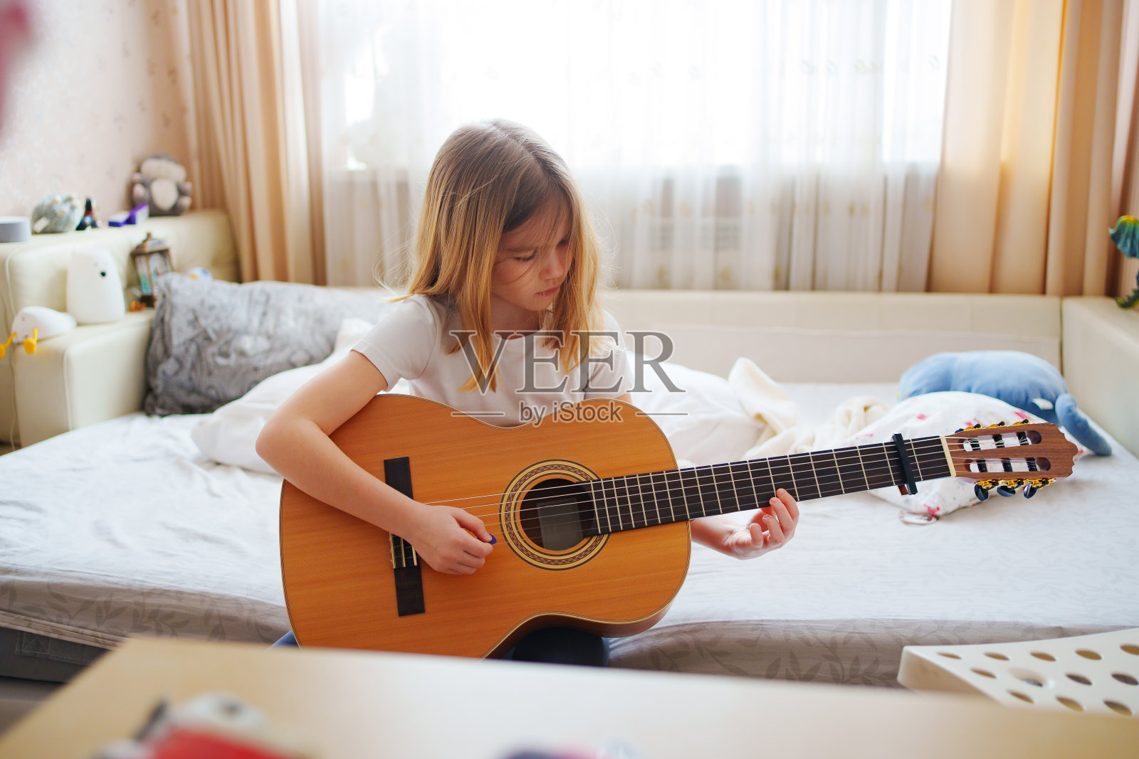 可爱的小女孩在学弹吉他。照片摄影图片