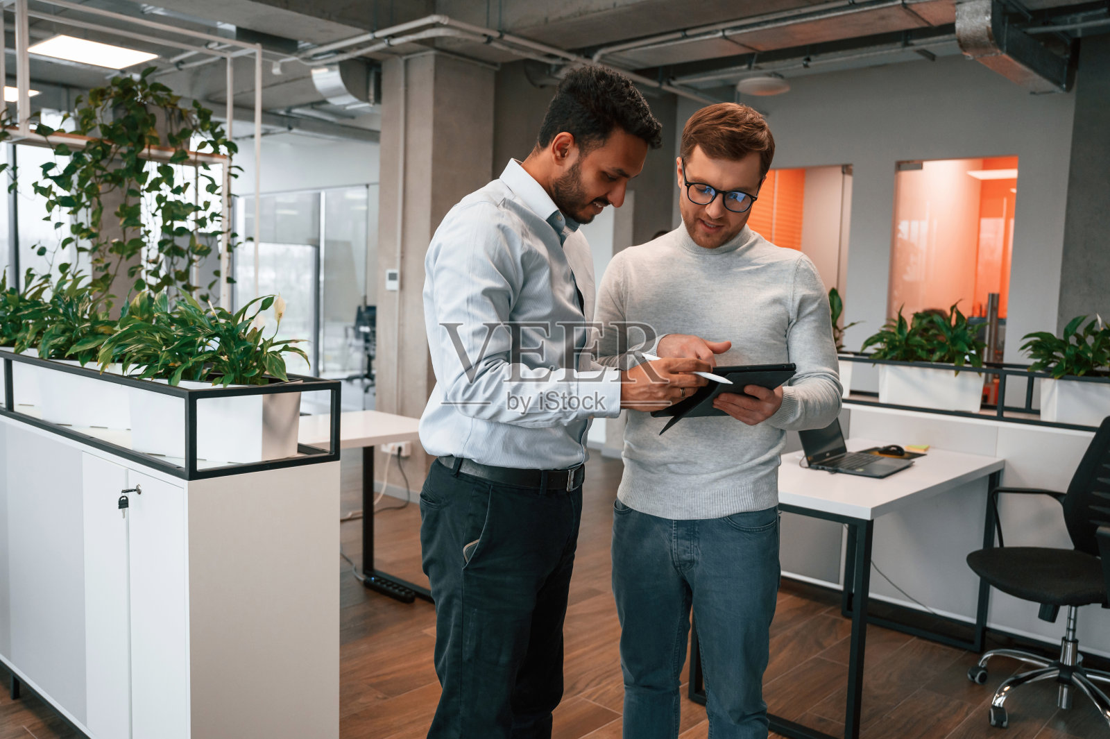 平板电脑中的信息。两个人一起在这间现代化的办公室里工作照片摄影图片