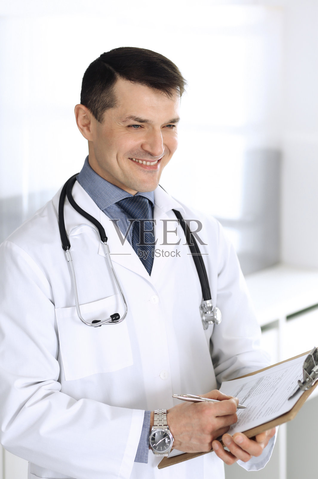 医生男子使用剪贴板填写用药历史记录。诊所医疗服务完善。在医院工作的医生。医学和保健概念照片摄影图片