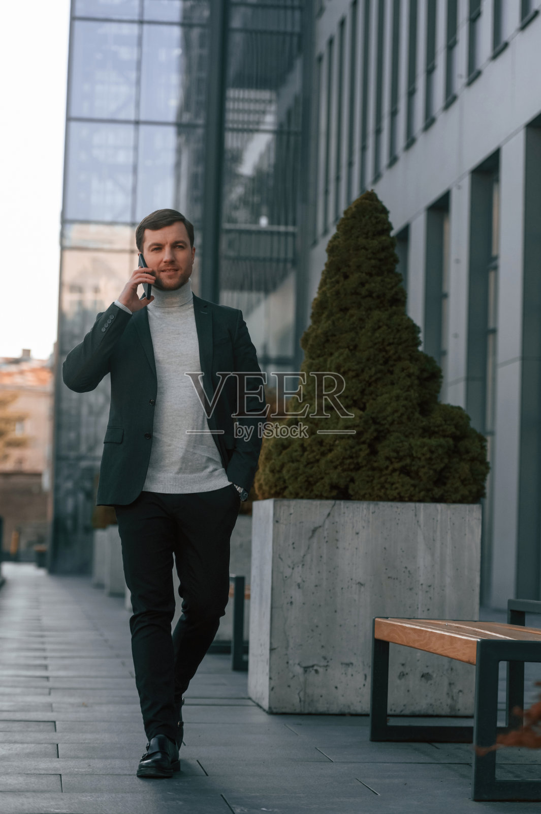 窗口后面穿着正装的帅哥正在使用智能手机照片摄影图片