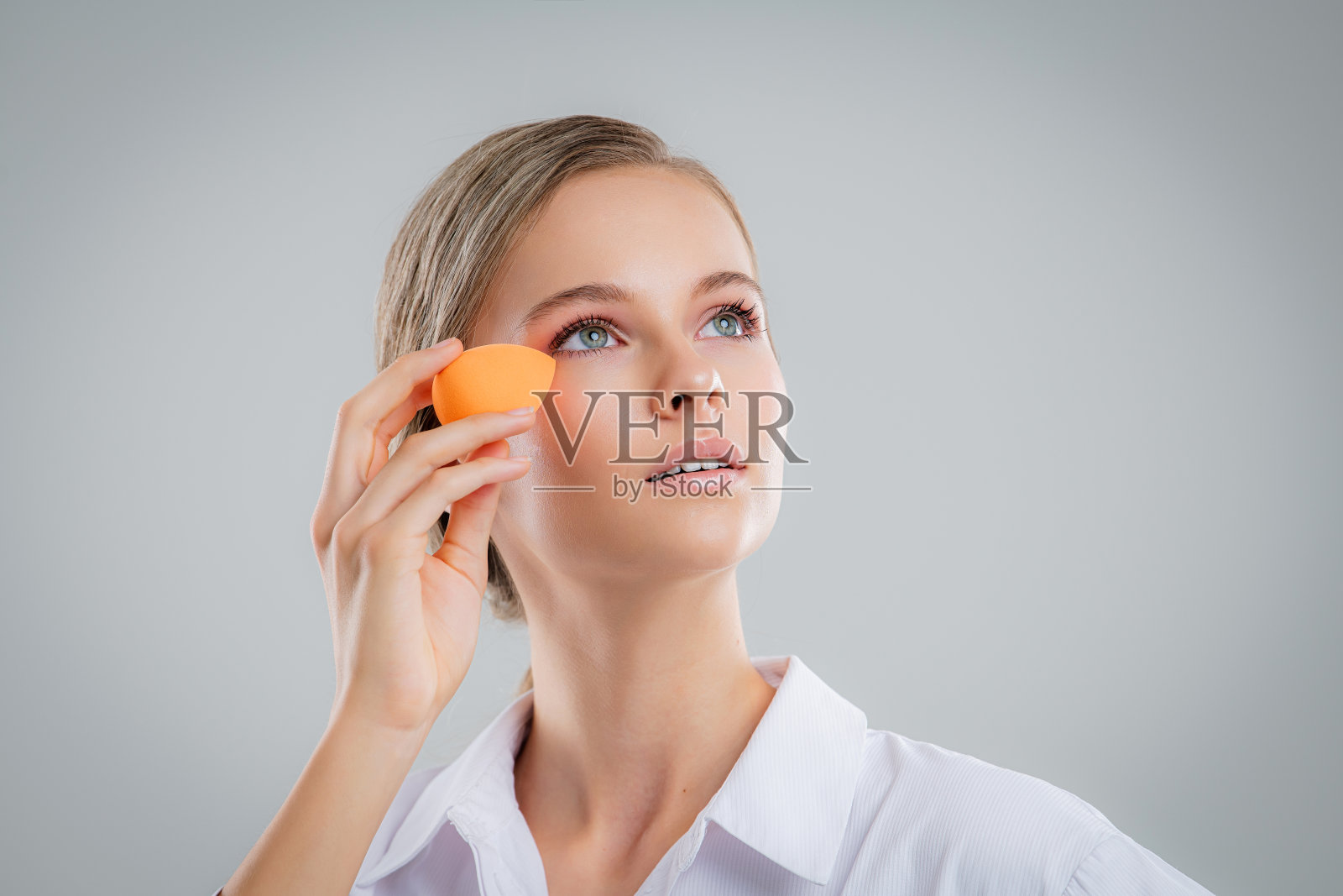 可爱美丽的自然黑发女孩清洁脸用棉花海绵微笑看着相机在白色背景。美容和水疗。照片摄影图片