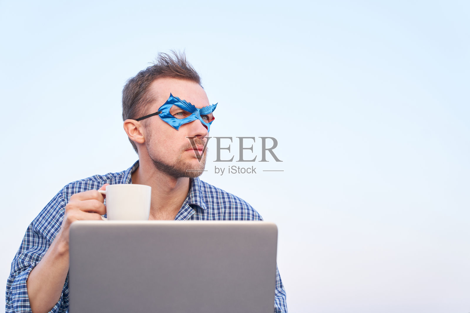 超级英雄电脑男戴着蓝色面具在户外用笔记本电脑拿着咖啡杯照片摄影图片
