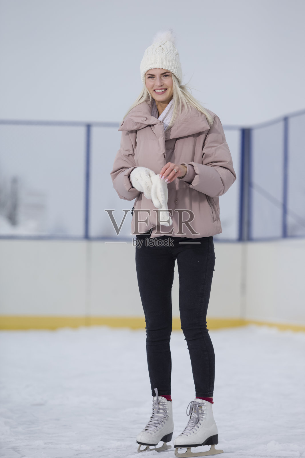 年轻的白人女孩在冬天与冰鞋摆姿势在一个下雪的冬季户外景观。照片摄影图片