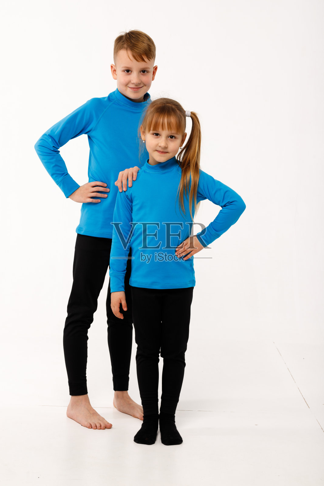 一个小女孩和她哥哥穿着保暖服。照片摄影图片