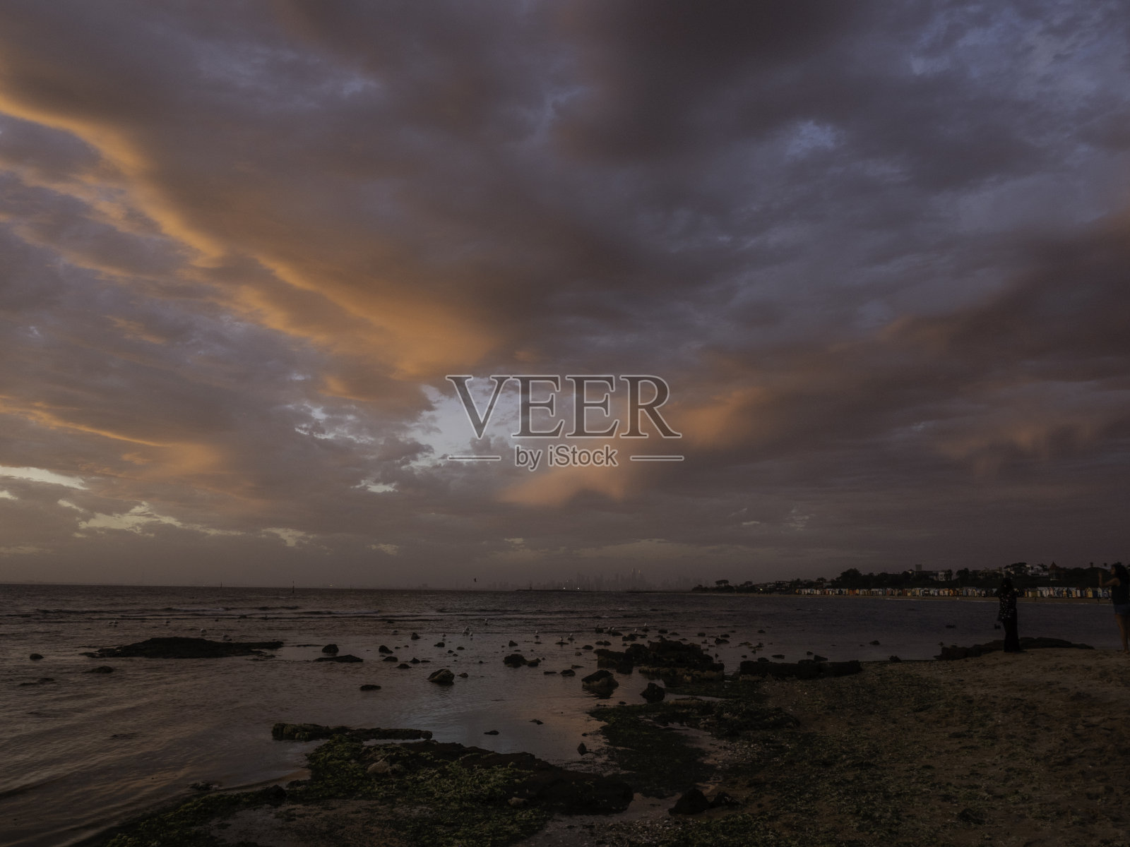 海滩和城市天际线上戏剧性的云层照片摄影图片