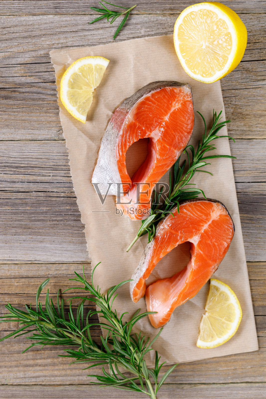 新鲜的红鲑鱼牛排配柠檬，迷迭香和胡椒在木制背景照片摄影图片