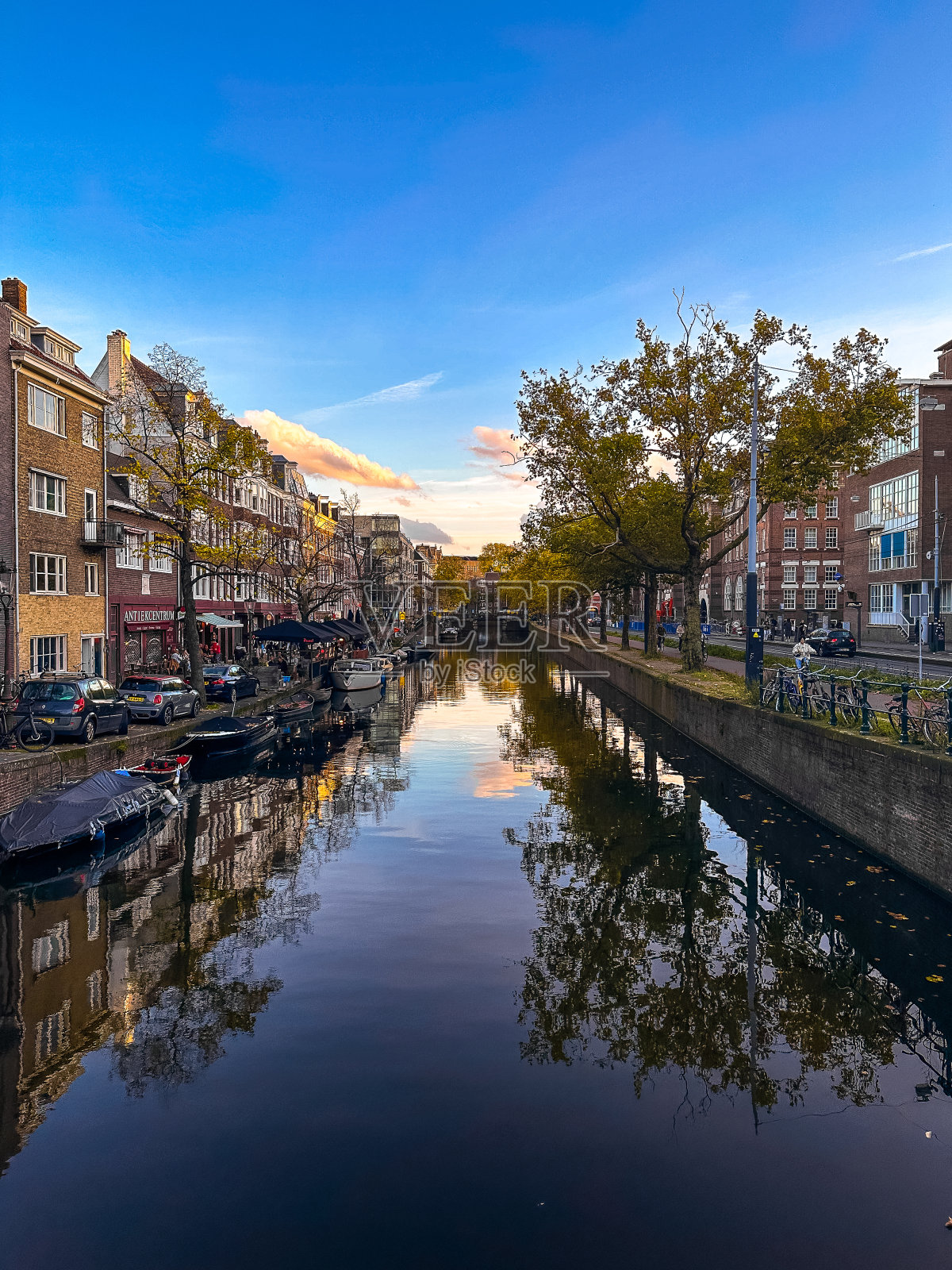 日落时分，荷兰阿姆斯特丹运河上的船只和自行车照片摄影图片