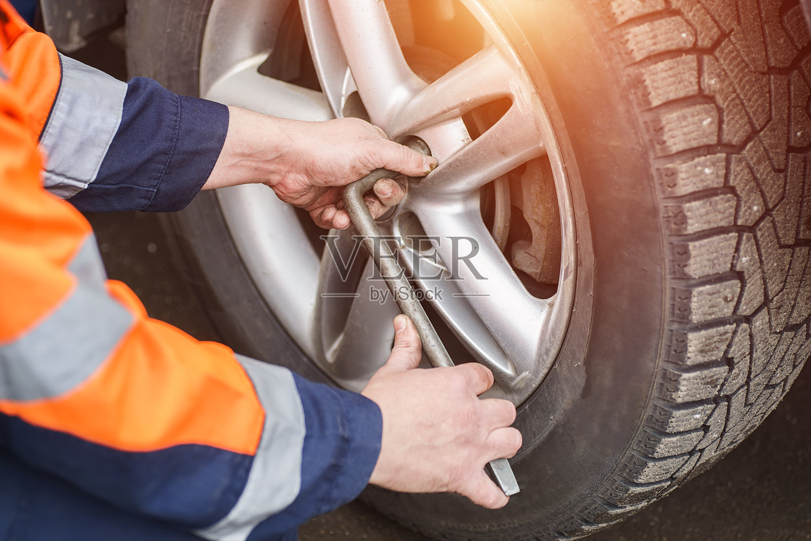 汽车车轮更换。自助式轮胎配件概念。用车轮扳手拧车轮螺母。照片摄影图片