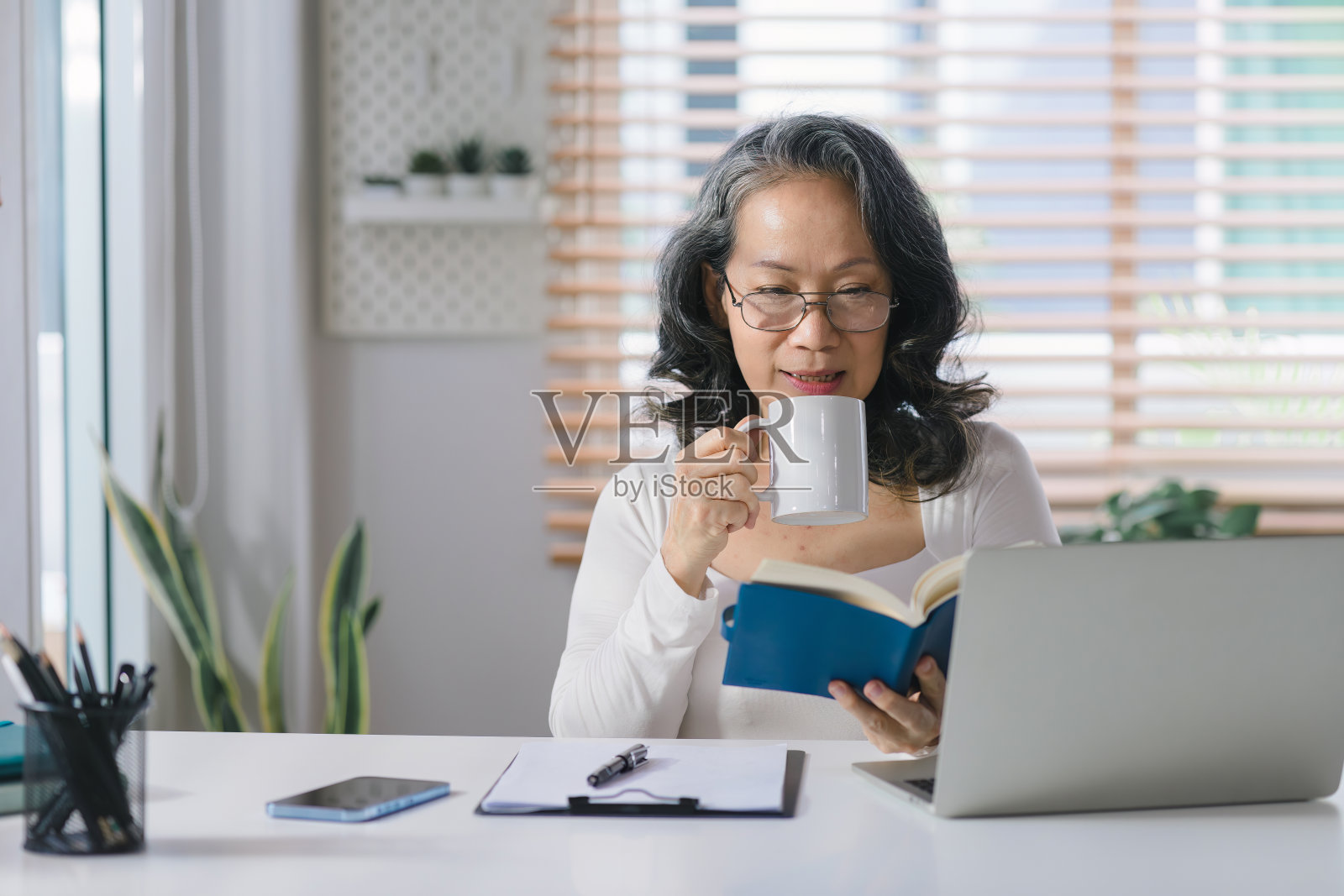 一个资深女企业家的肖像从她的家庭办公室远程工作。照片摄影图片