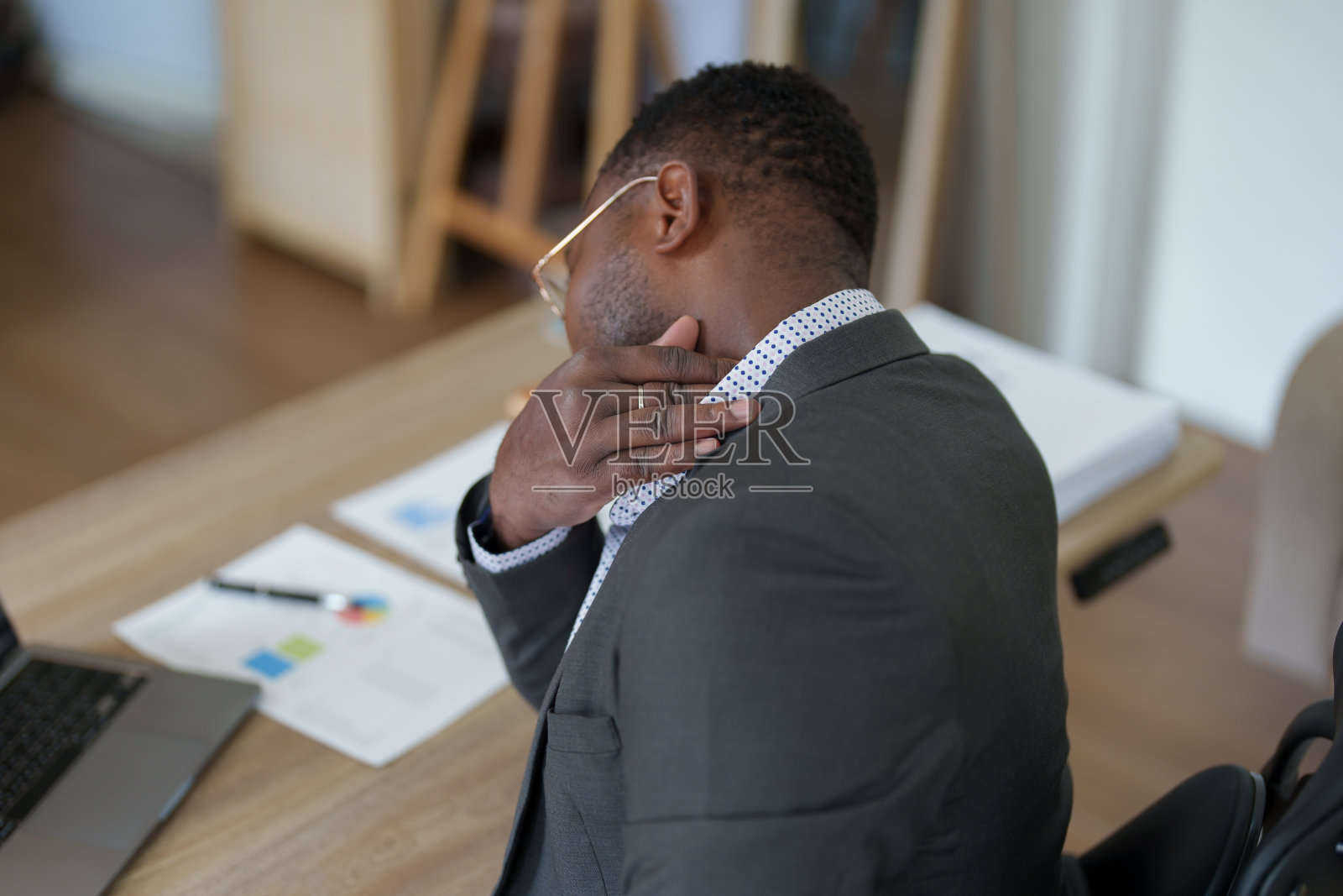 精疲力竭美国非洲商人在压力工作与许多文书文件，偏头痛发作，自由职业者，在家工作照片摄影图片