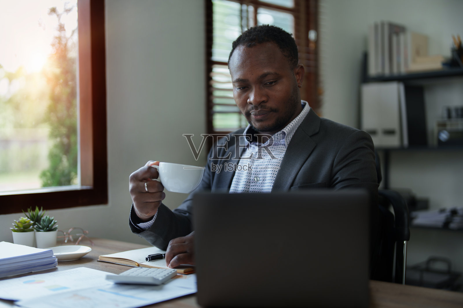 中年男子美国非洲人使用笔记本电脑与计划工作的财务文件，税务，外汇，会计和财务顾问照片摄影图片