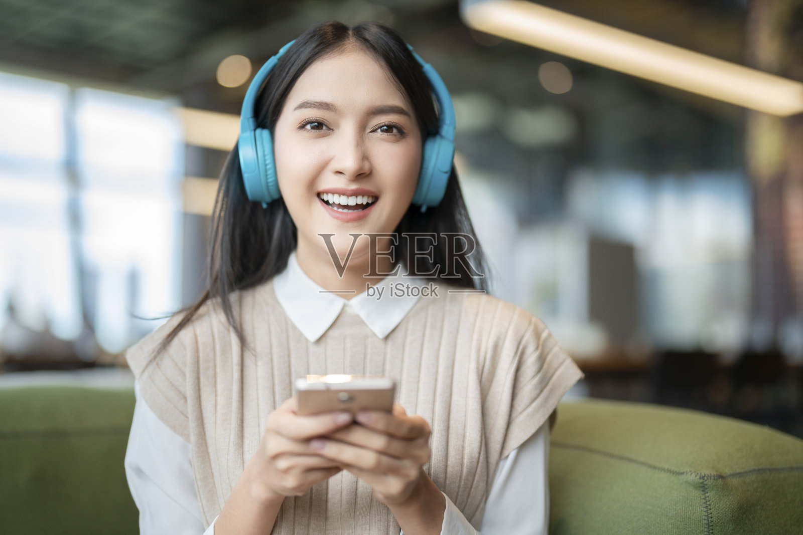 放松快乐的休闲亚洲女性成年女性休闲布享受听音乐从流媒体在线播放音乐播放列表应用在智能手机上通过耳机在沙发沙发在共同工作空间照片摄影图片