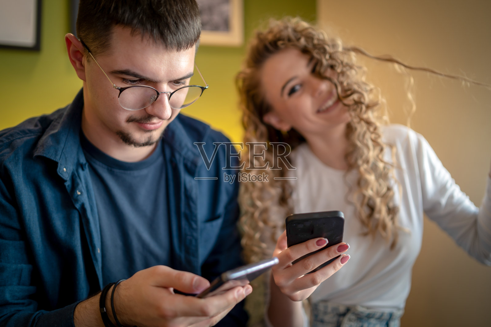 couple having a coffee date in café. Drinking coffee and chatting while using smartphone together照片摄影图片