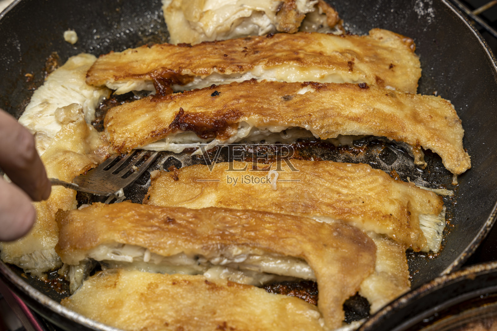 厨师用叉子检查鱼是否熟了照片摄影图片