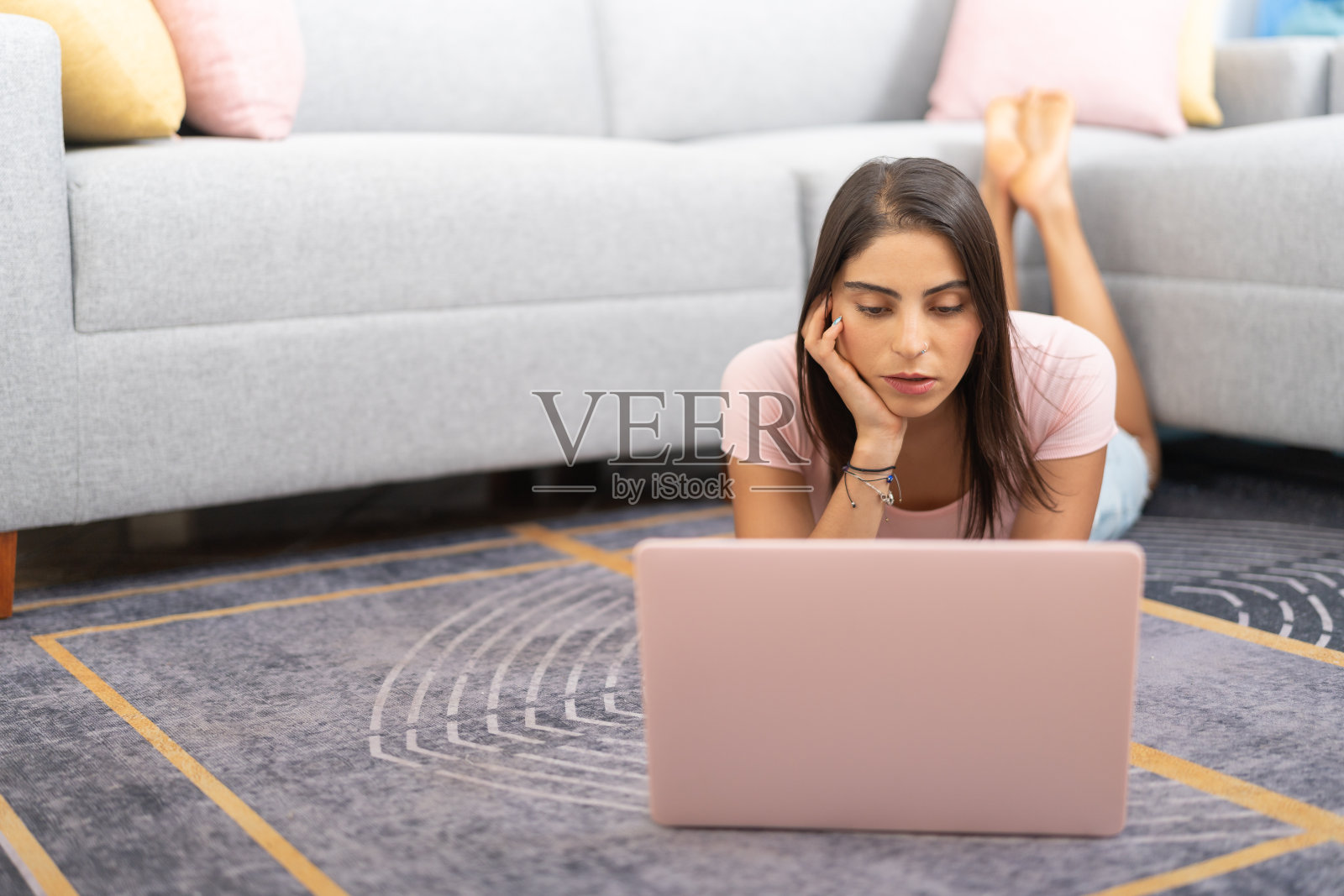 认真的年轻女人，趴在客厅地板上，用笔记本电脑工作照片摄影图片