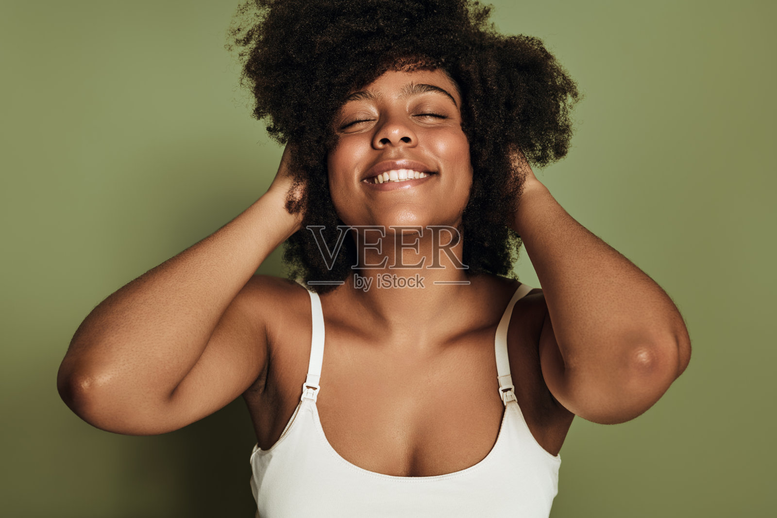 快乐的年轻民族女士抚摸头发，闭着眼睛微笑照片摄影图片