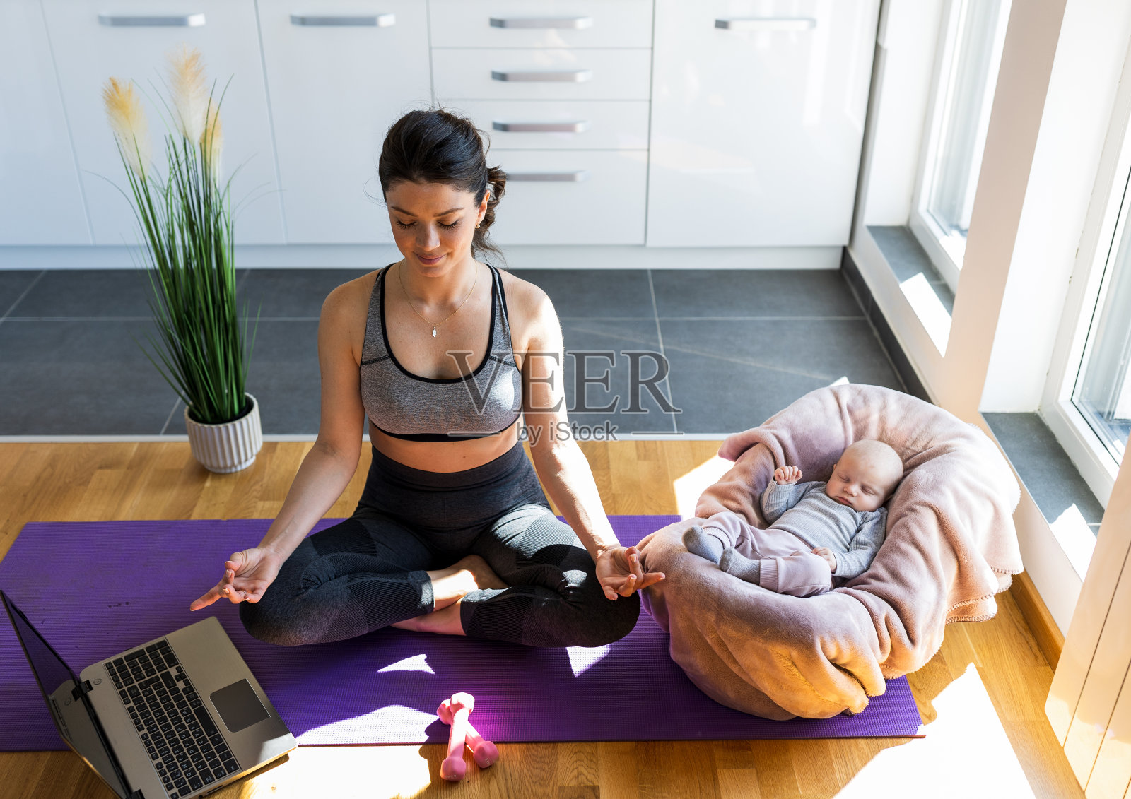 漂亮的妈妈在家里冥想和锻炼，而婴儿睡觉照片摄影图片