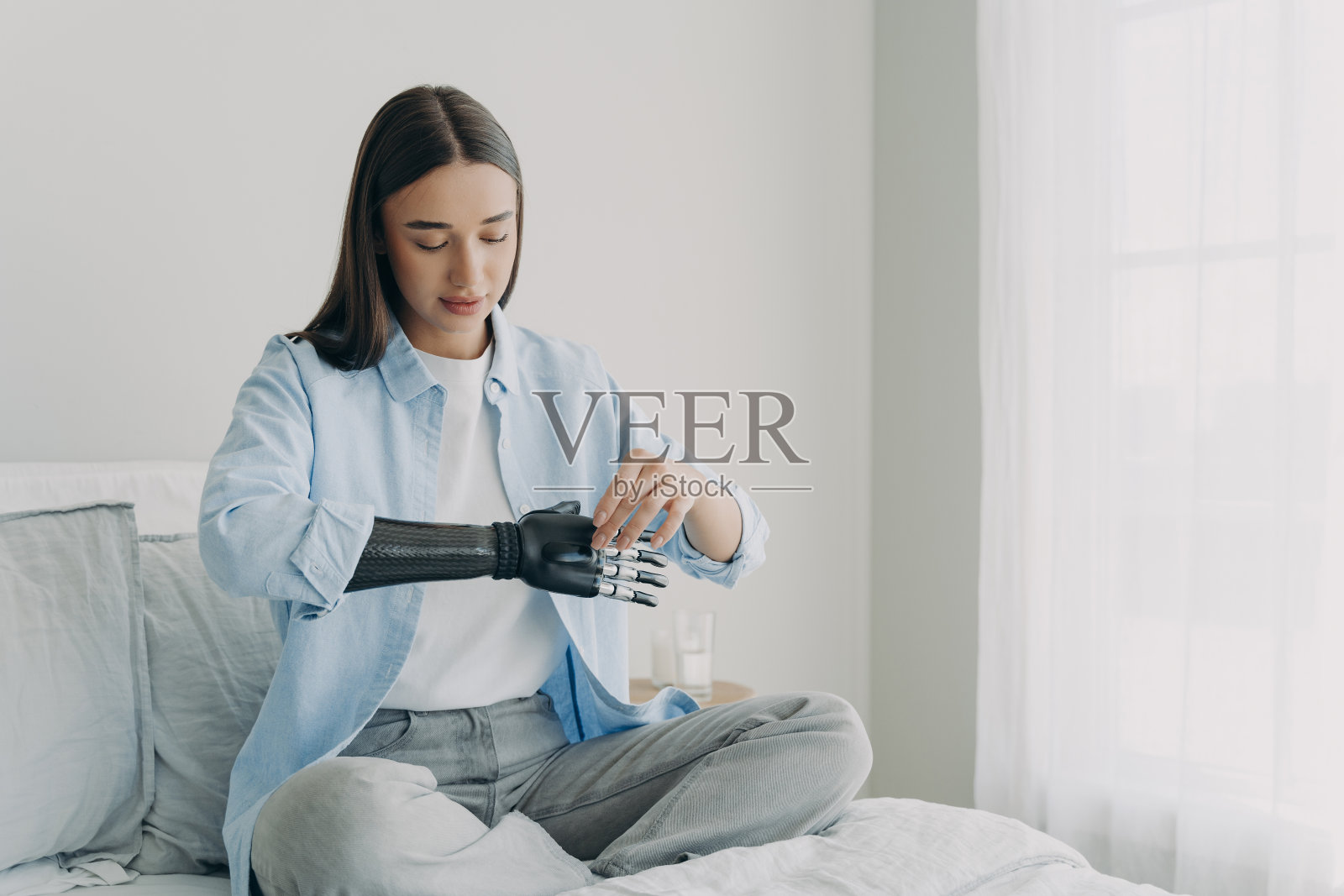 残疾年轻女子设置神经控制假体参数。仿生人工手臂。照片摄影图片