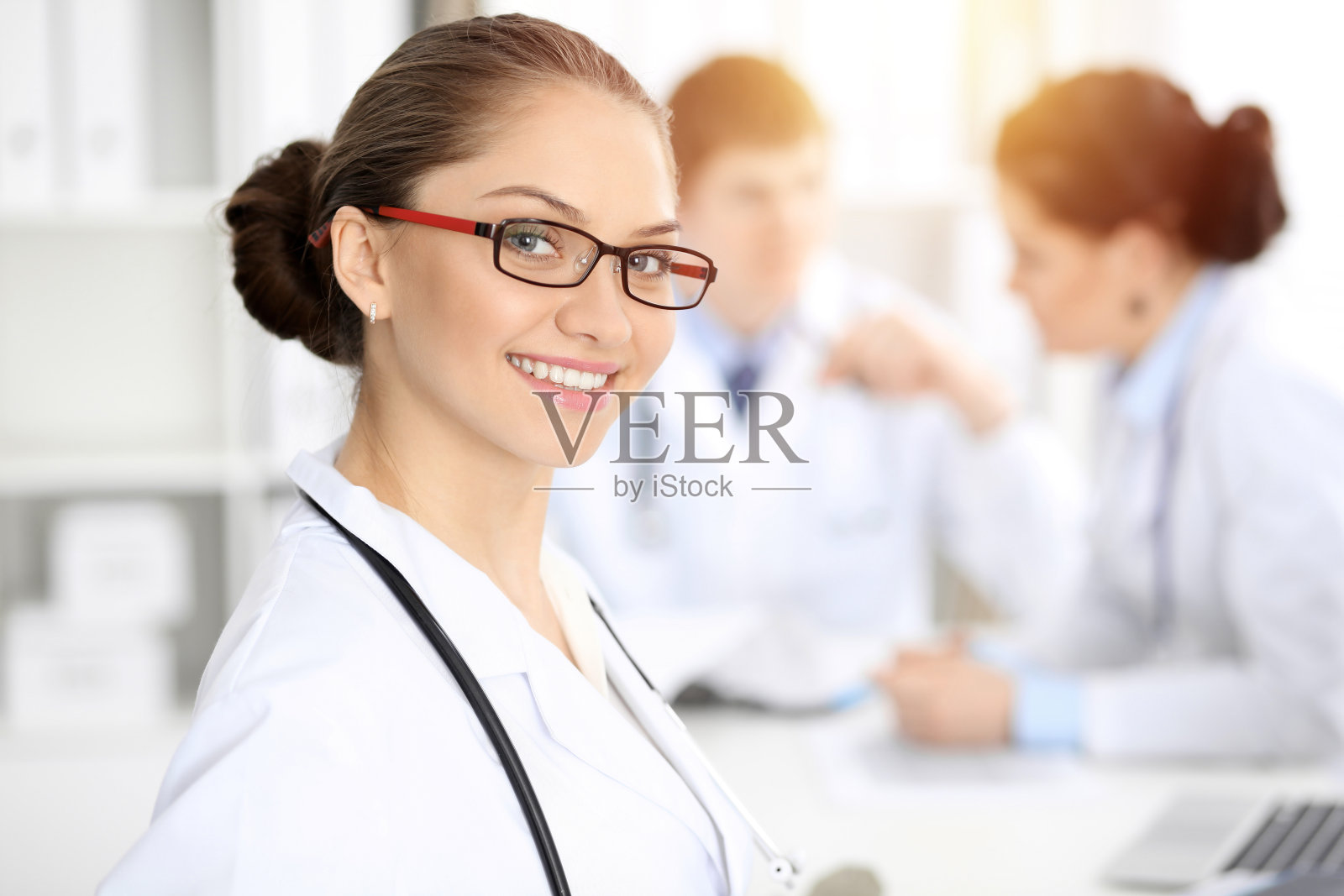 快乐的微笑女医生坐着，看着相机在会议上的医务人员。医学的概念照片摄影图片