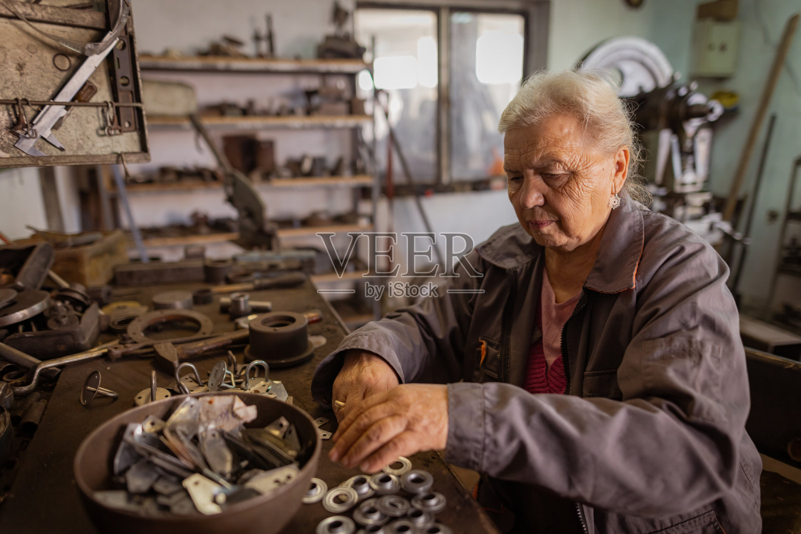 老年妇女在她的车间金属加工照片摄影图片