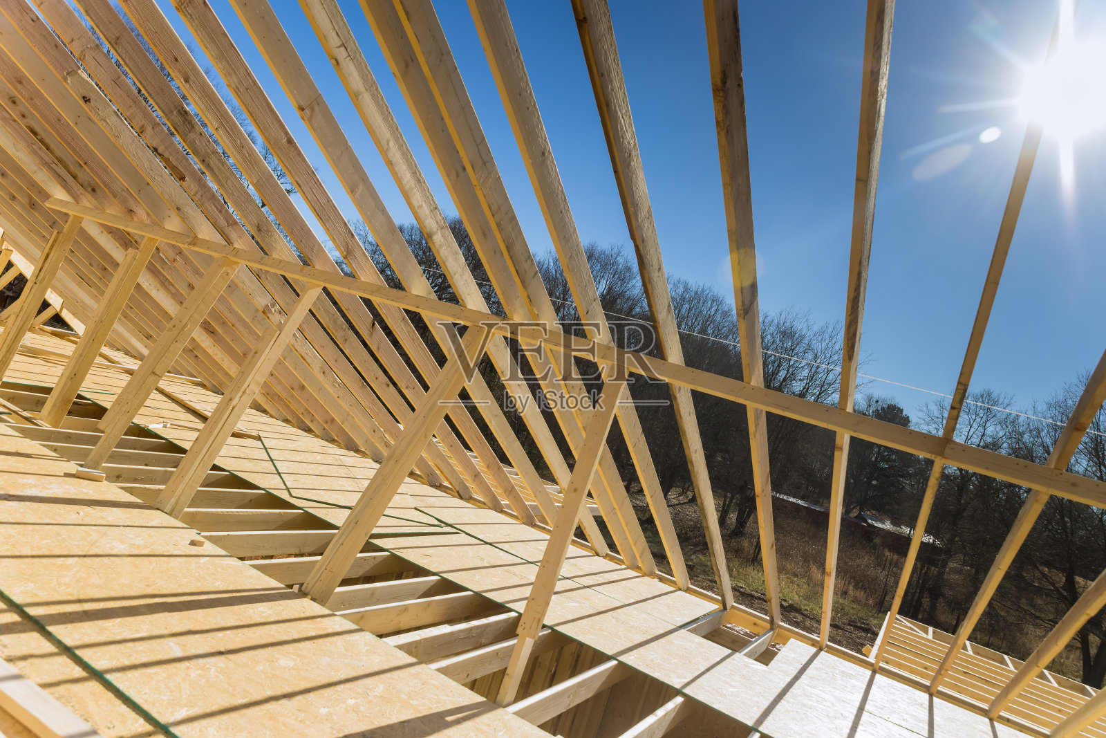 一个新的木材桁架框架建筑的结构框架目前正在建造，其中包括椽、屋顶梁和木搁栅作为结构框架的一部分照片摄影图片