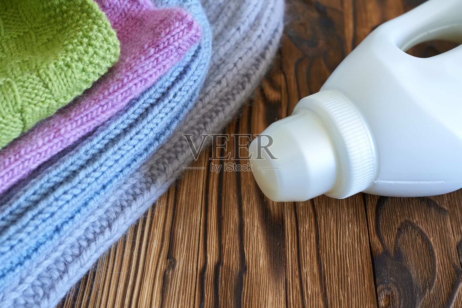 针织衣服和一瓶衣服护理凝胶在木制背景。概念是针织服装的护理。照片摄影图片