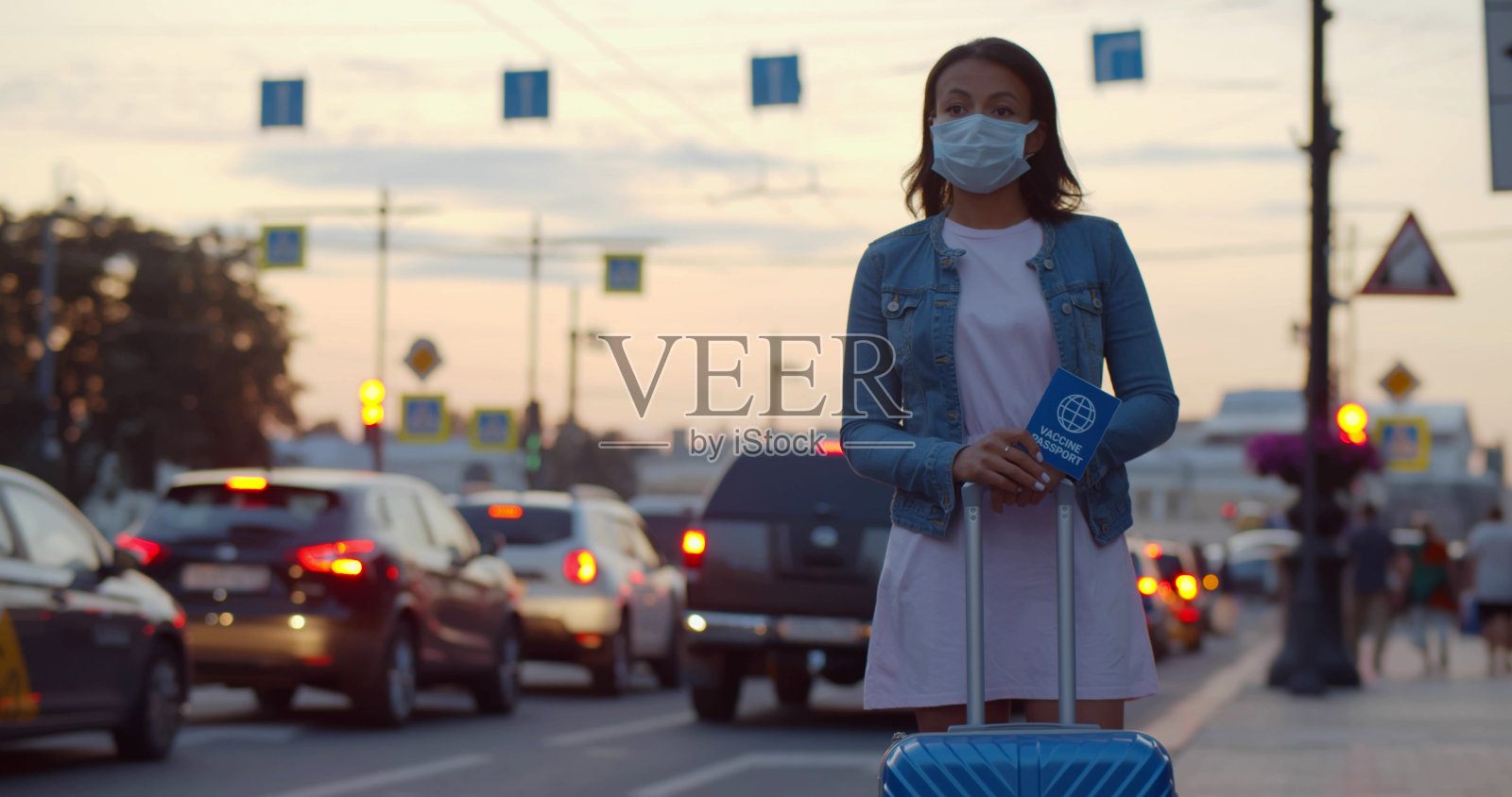 非洲裔美国妇女的肖像，戴着安全口罩，拿着疫苗护照和行李箱等待出租车照片摄影图片