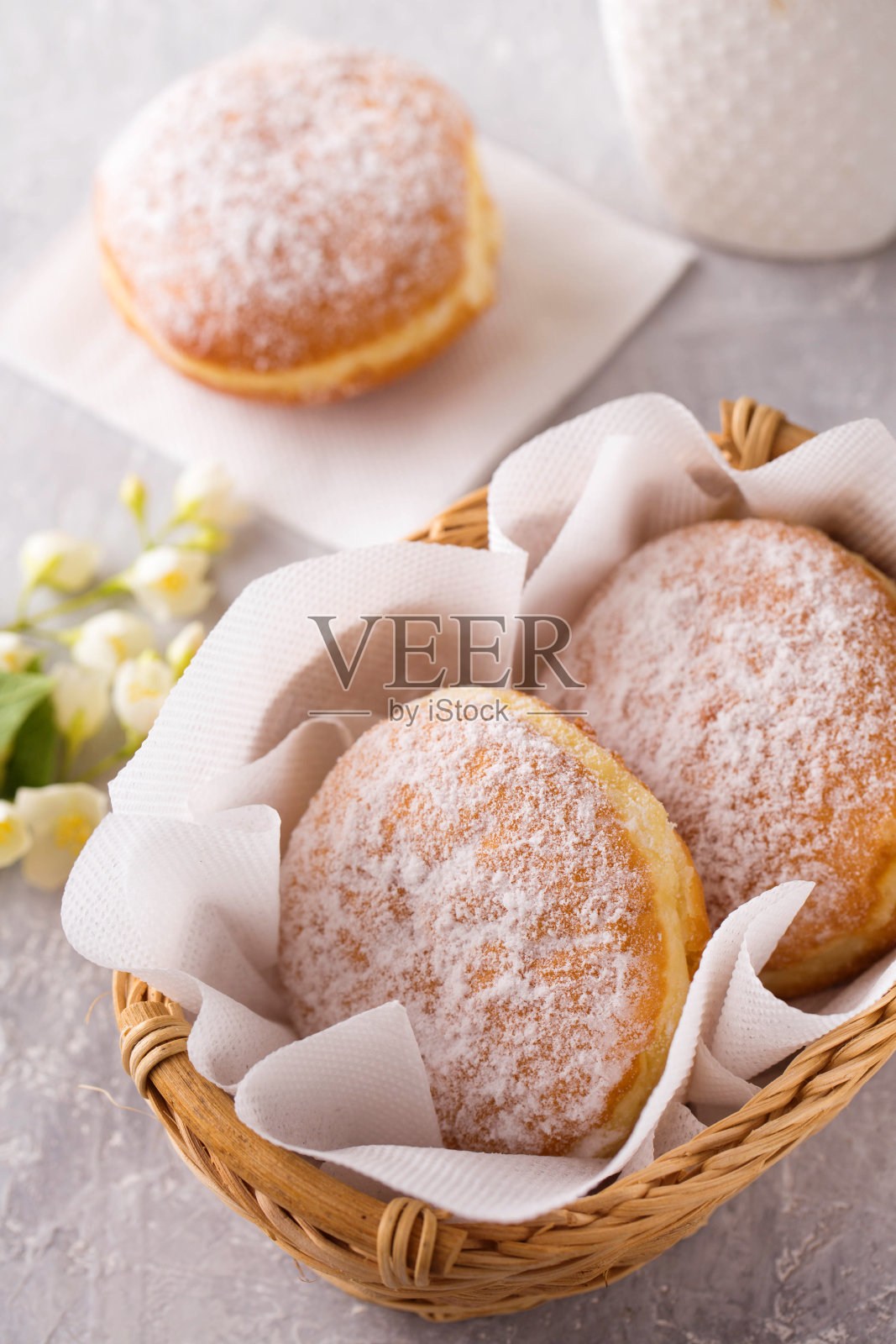 红色美味的柏林甜甜圈，馅料撒上糖粉，放在灰色背景的篮子里照片摄影图片